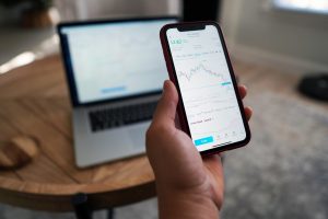 Smartphone, hand, stocks — Prop Trading Firms Empower Traders With Tools, Funding, and Growth Pathways
